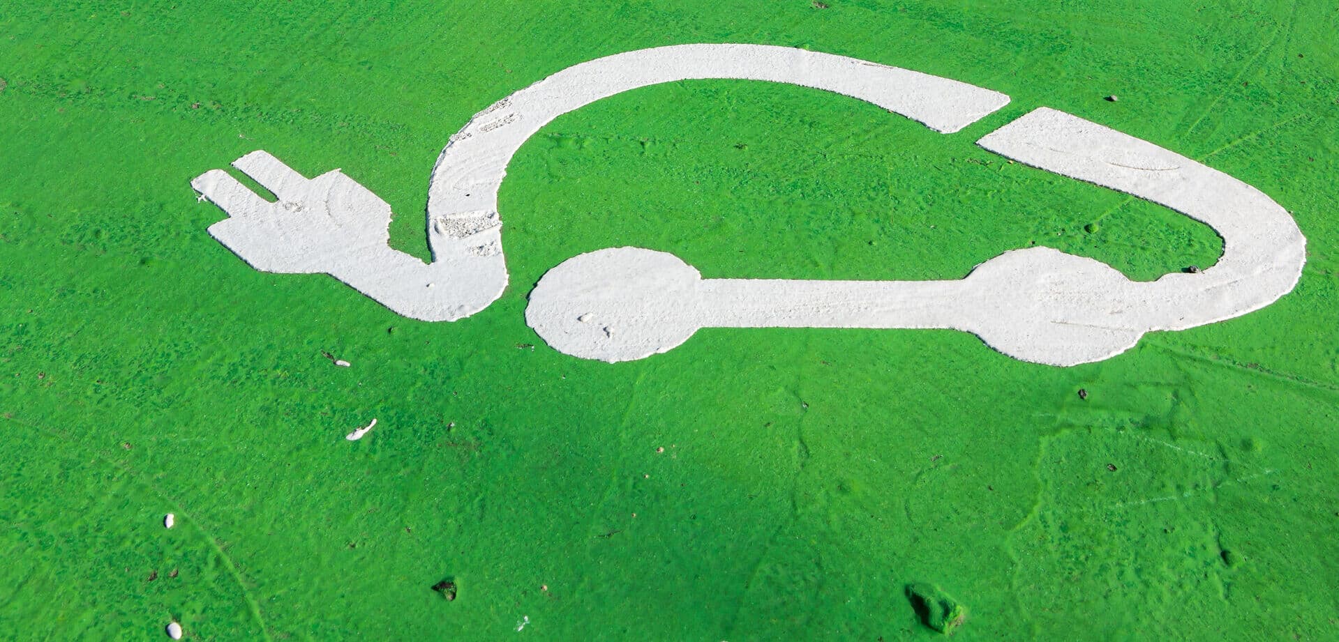 white outline of car with plug on green ground