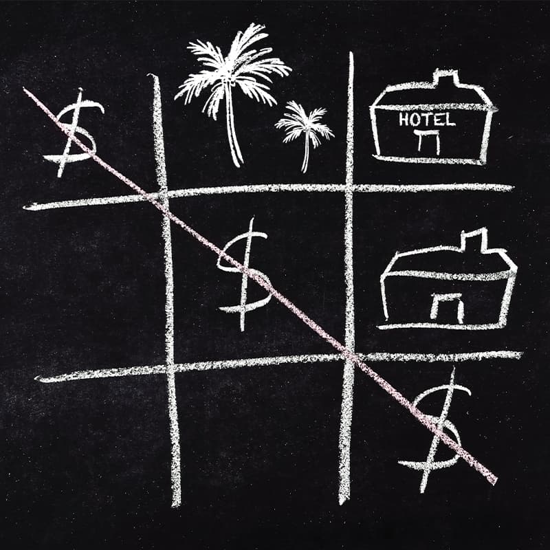 A game of noughts and crosses on a blackboard, but with US dollar signs completing a diagonal, with drawings of palm trees and hotels in the other spaces