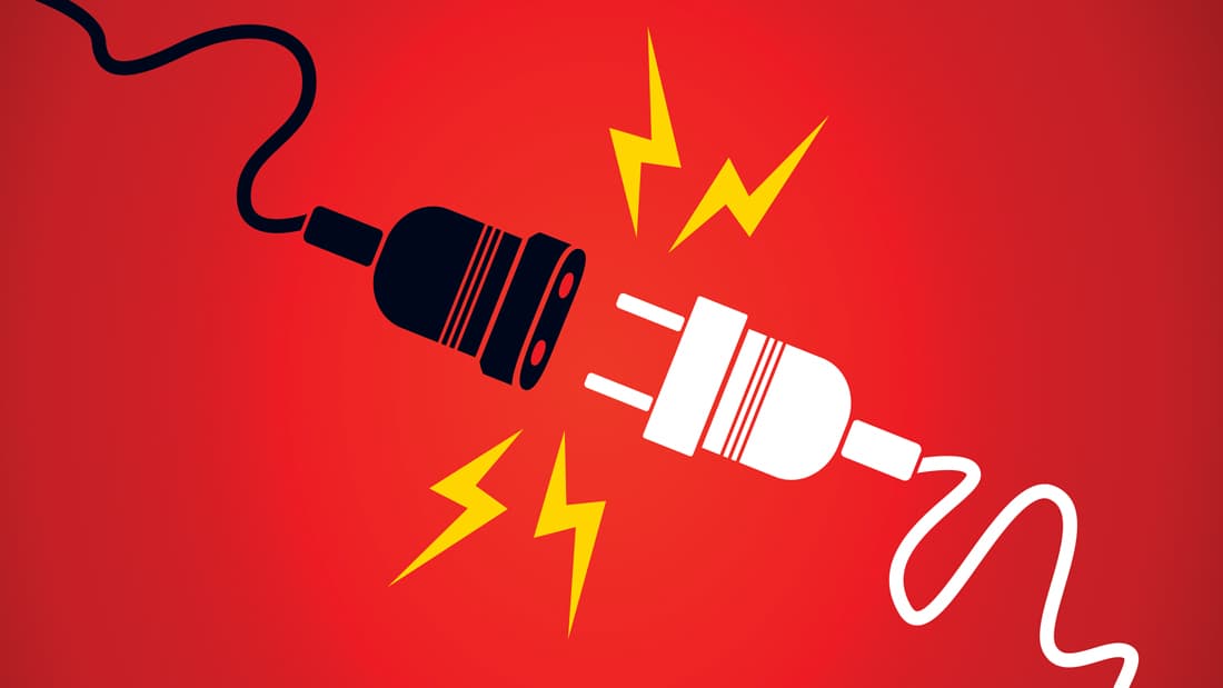 A white plug disconnecting from a black extension cable on a red background